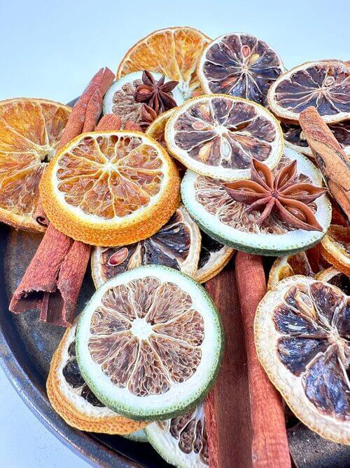 Dried citrus, star anise, and cinnamon display on a rustic platter, autumnal aroma arrangement.